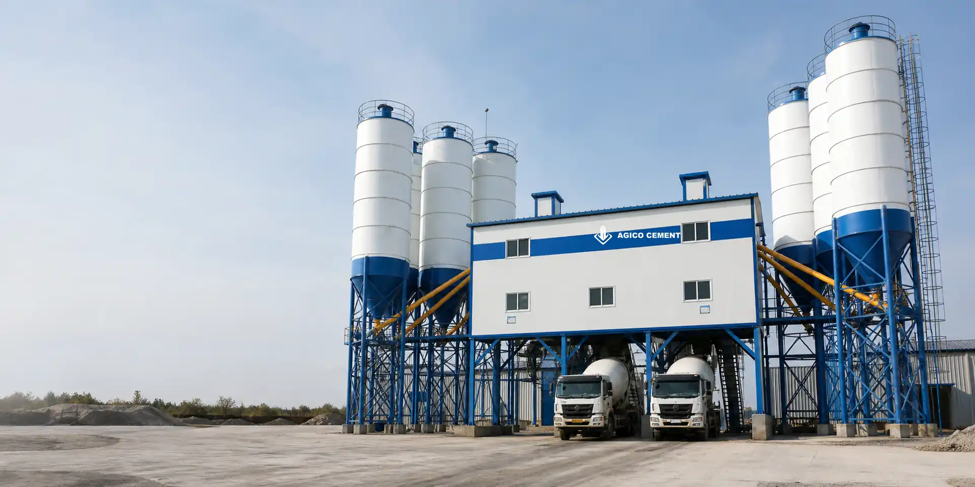 AGICO double-line central mix concrete plant with shared mixing building, side silo banks and two truck loading bays