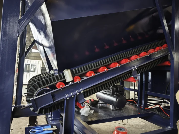 Aggregate transfer belt and red support rollers beneath a batching hopper