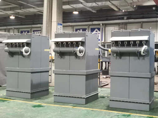 Pulse-cleaned dust filter units with compressed-air manifolds in a workshop