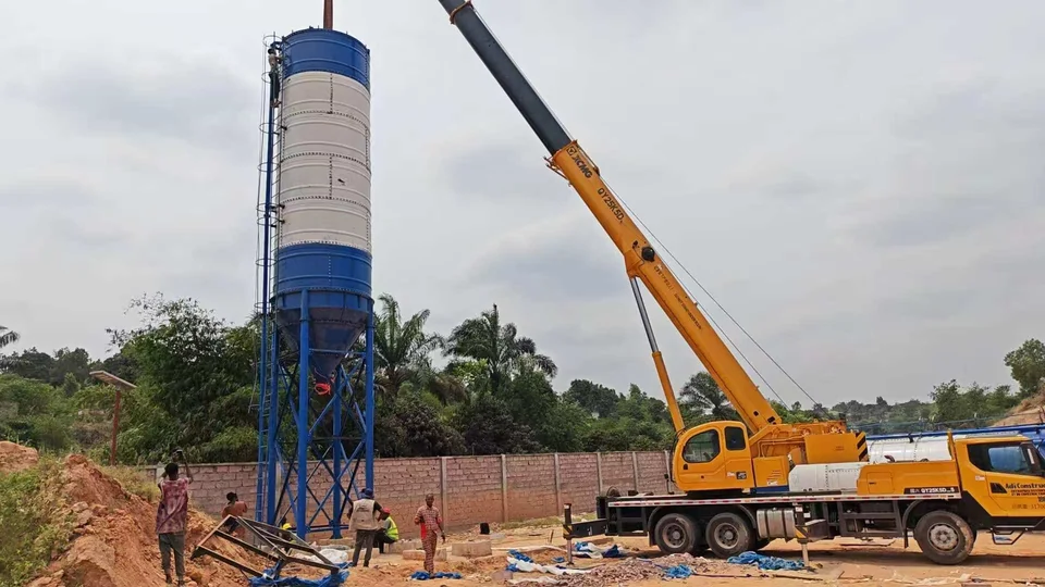Crane beside an upright cement silo during a batching-plant installation stage